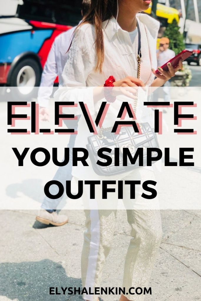 Elevate your simple outfits. Women walking across the street wearing a white outfit. She has a red scrunchy around her wrist and is holding a red phone. 